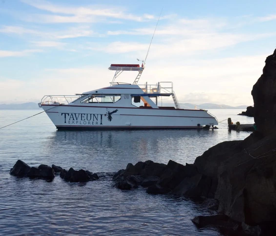 A boat rests in the sea near some rocks A boat rests in the sea near some rocks